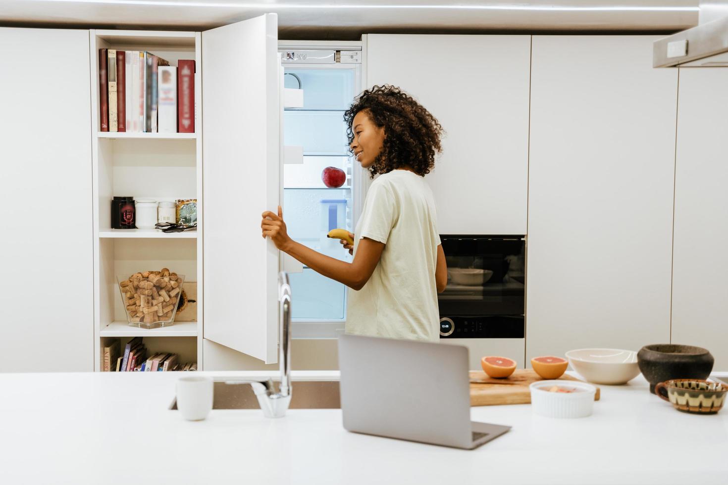 giovane donna nera che apre il congelatore mentre prepara la colazione in cucina foto