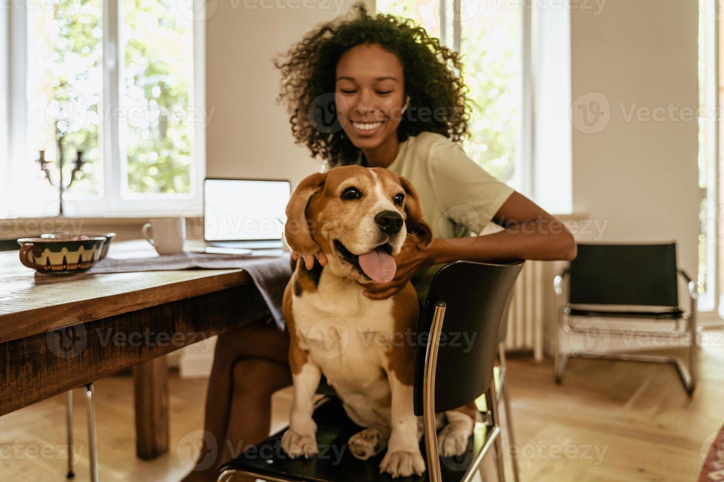 giovane donna nera che accarezza il suo cane mentre è seduta a tavola foto