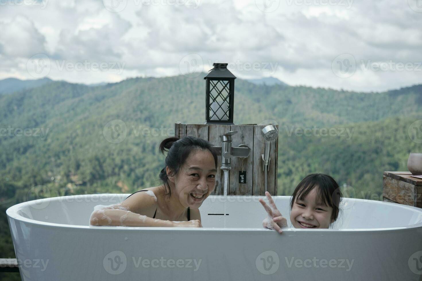 asiatico famiglia, mamma e bambino giocando insieme, senza fretta rilassare nel vasca da bagno, godere felicemente con panoramico montagna gamma Visualizza di tropicale paesaggio nel naturale scenario viaggio ricorrere per vacanza vacanza. foto
