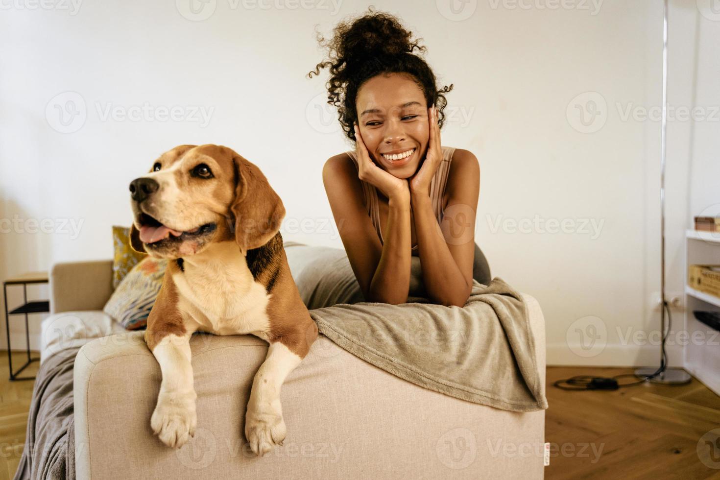 giovane donna nera che ride mentre riposa con il suo cane sul divano foto