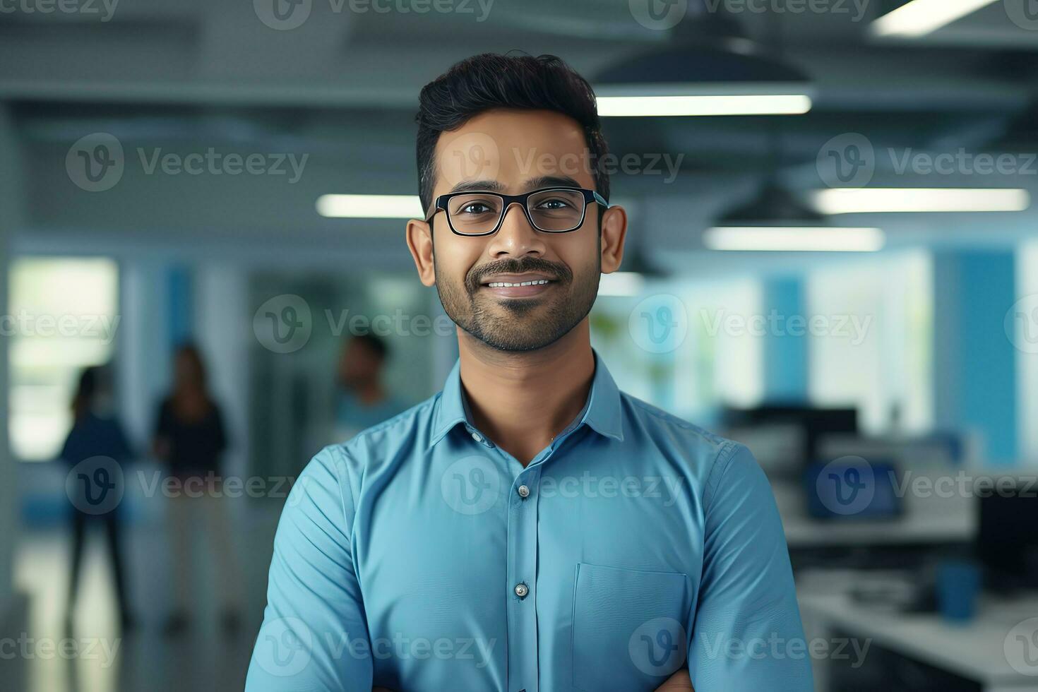 ai generato un' giovane indiano maschio progettista, ingegnere, architetto chi è indossare bicchieri e un' blu camicia sorridente in piedi nel il ufficio e guardare a il telecamera foto