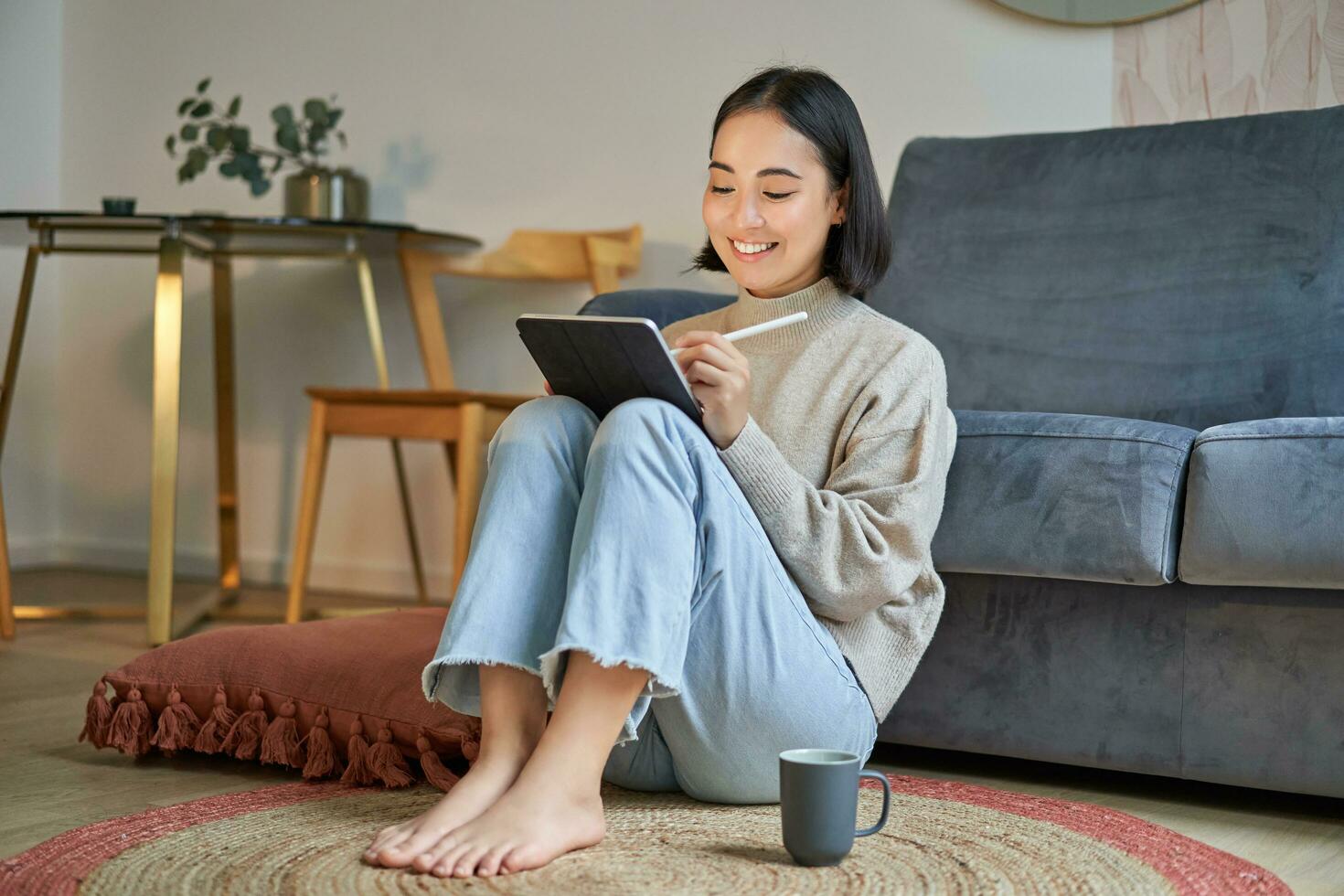 ritratto di creativo giovane donna disegno su digitale tavoletta con penna, potabile caffè, Lavorando a partire dal casa, Piano e design nuovo progetto foto