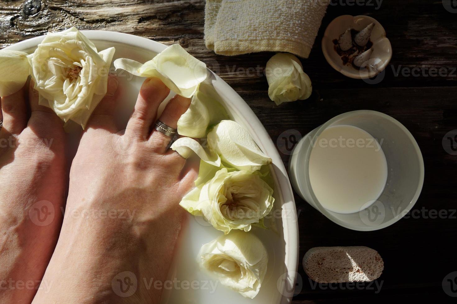 femmina a piedi nudi nell'acqua con latte e rose bianche. bellissimo pediluvio. foto