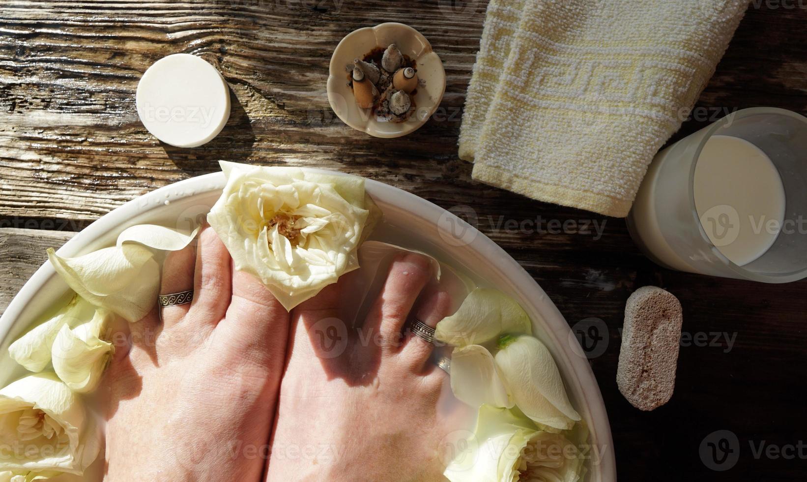 donna a piedi nudi nell'acqua con latte e rose bianche. foto