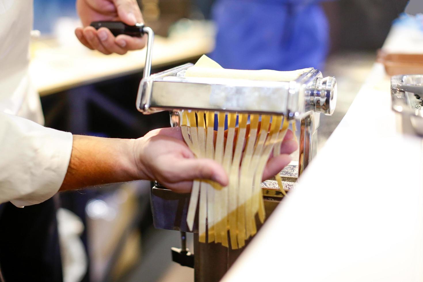 chef che fa la pasta con la macchina, pasta fresca fatta in casa foto