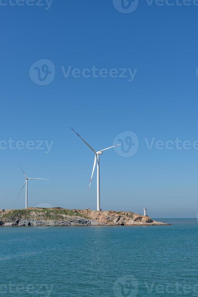sull'isola in mezzo al mare, molte pale eoliche sono installate sotto il cielo azzurro foto