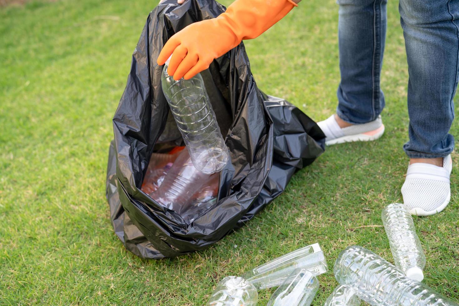 volontaria di una donna asiatica porta bottiglie di plastica d'acqua nella spazzatura del sacco della spazzatura nel parco, ricicla il concetto di ecologia dell'ambiente dei rifiuti foto