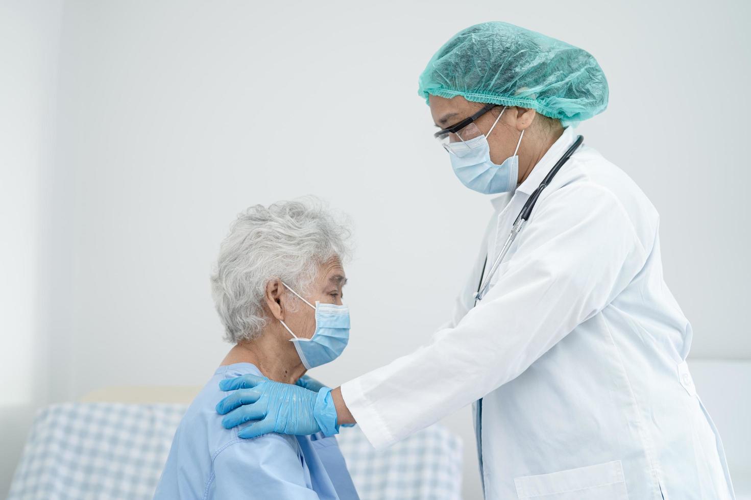 il medico aiuta la donna anziana o anziana asiatica paziente che indossa una maschera facciale in ospedale per proteggere l'infezione di sicurezza e uccidere il coronavirus covid-19 foto