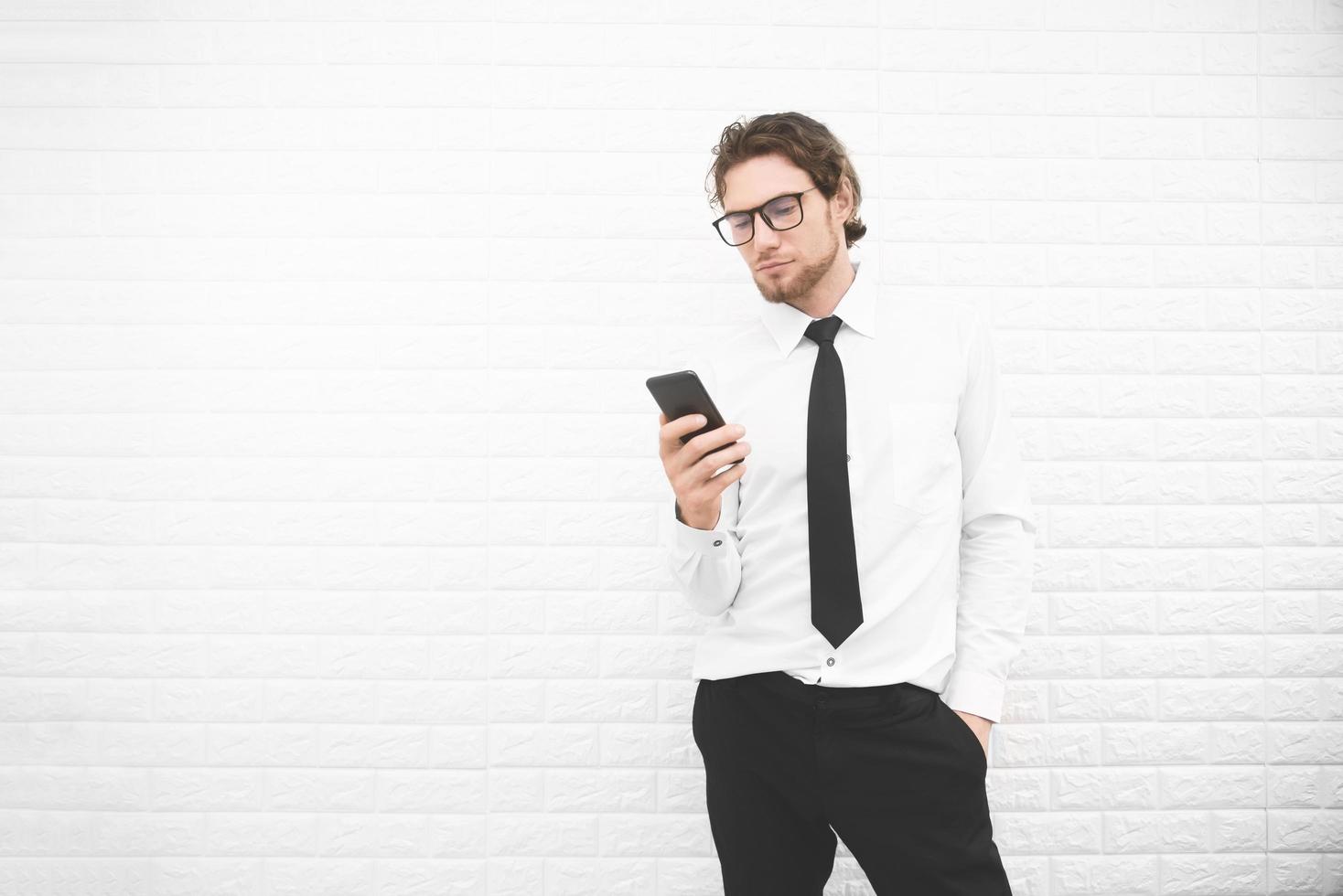 uomo d'affari in uniforme formale e utilizzando smartphone o telefono cellulare davanti al muro bianco, concetto di business e moda. elaborazione incrociata e tono diviso instragram come processo foto