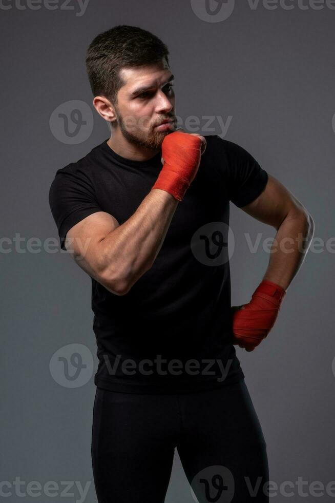 pensieroso atletico uomo con boxe polso impacchi su grigio sfondo foto