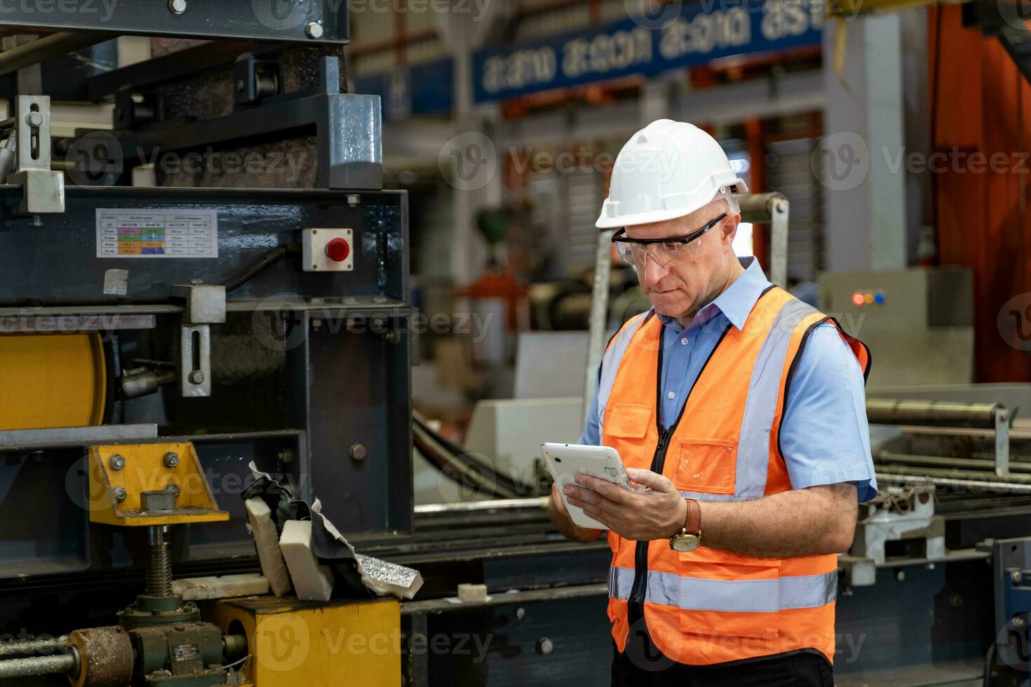 caucasico industriale lavoratore è utilizzando digitale tavoletta per prendere Nota mentre ispezionando dentro il metallo foglio zincato tetto fabbrica per sicurezza industria foto