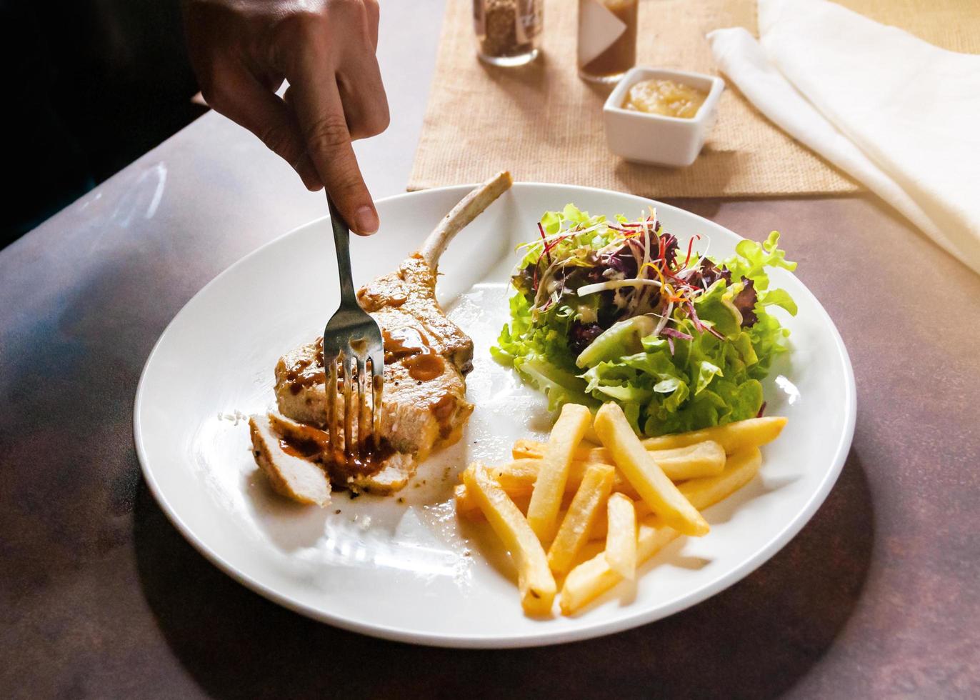 bistecca di braciola di maiale con insalata e patatine fritte foto