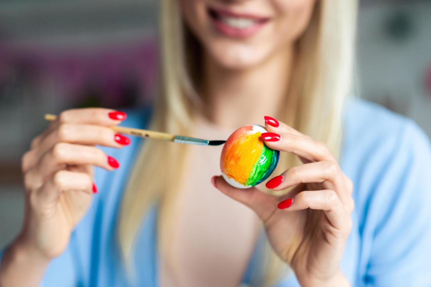 la donna bella e sinceramente sorridente dipinge con cura l'uovo di Pasqua foto