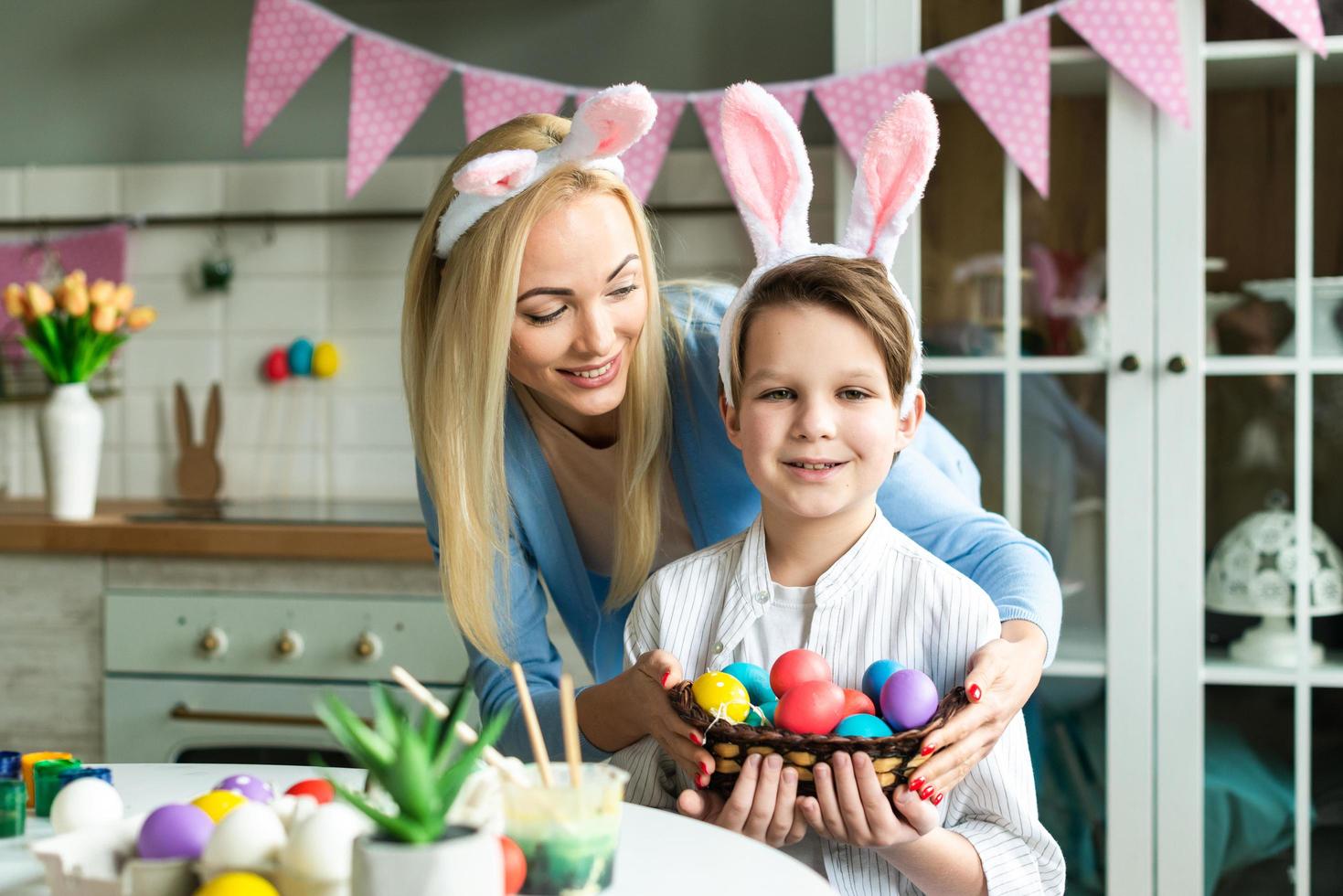 la madre felice e il suo figlioletto si stanno preparando per la Pasqua, colorando le uova foto