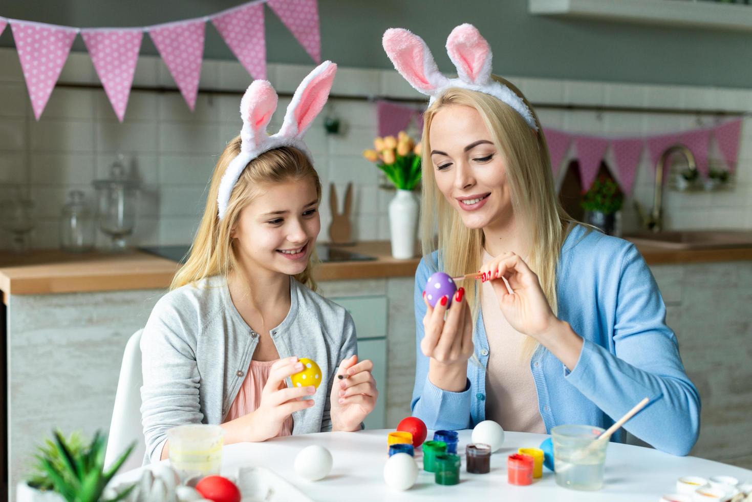 madre e figlia dipingono le uova. portano le orecchie da lepre foto