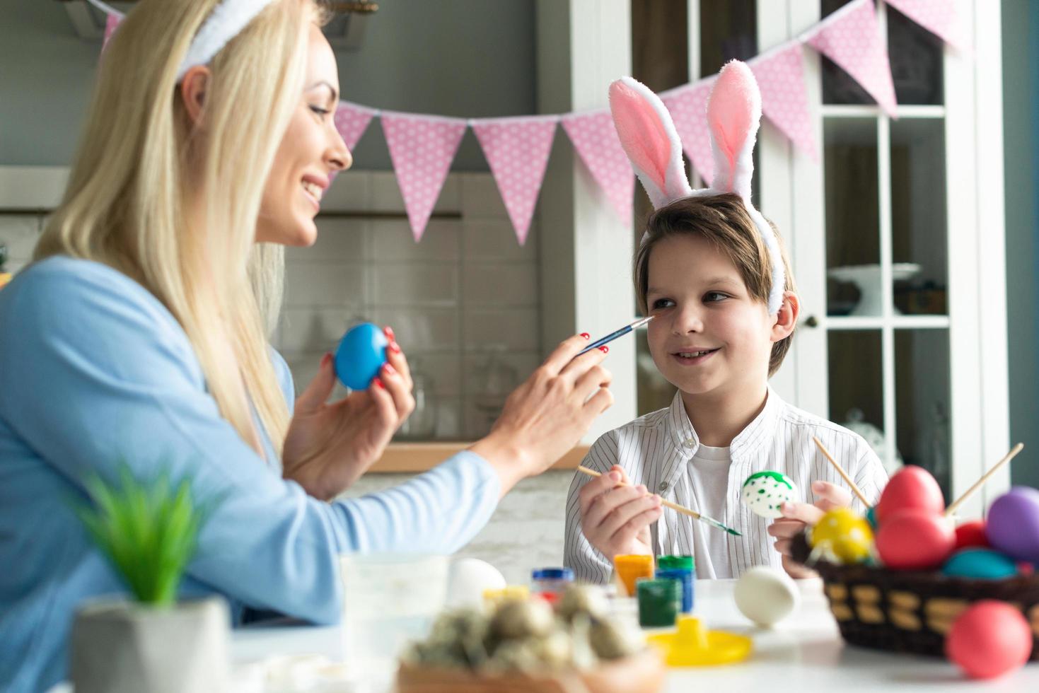 madre e figlio con fasce per orecchie da coniglio e uova di Pasqua dipinte a casa foto
