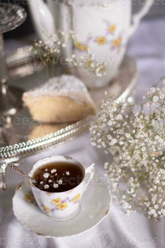 bianca ancora vita con torta di formaggio e gypsophila e tazza di Tè, leggero e arioso foto