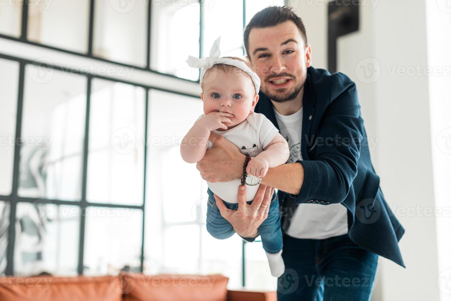 uomo bello e sorridente che tiene la sua amata piccola figlia. sembra che un bambino stia volando foto