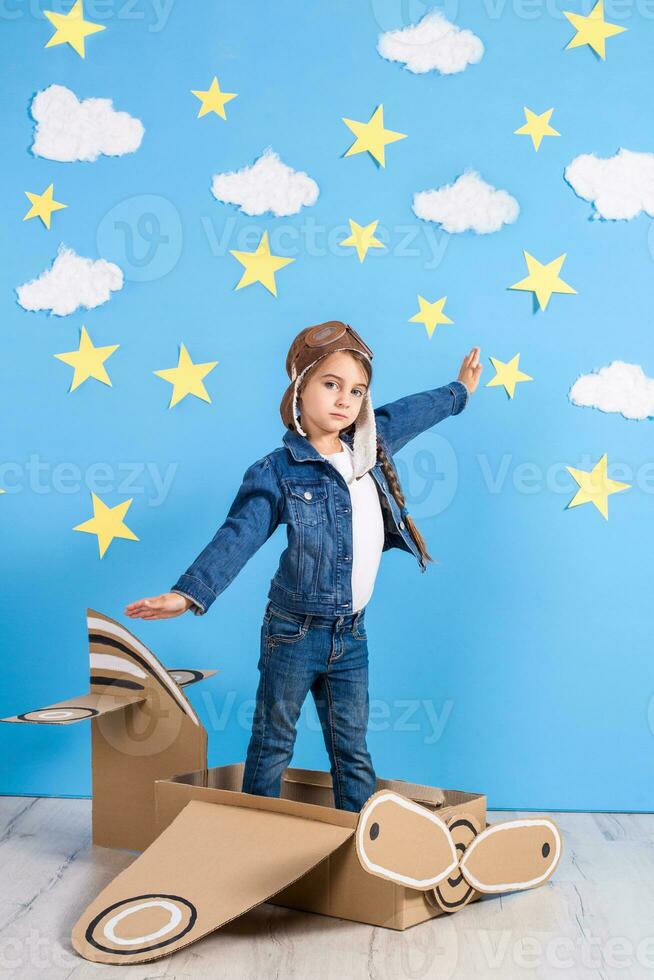 poco bambino ragazza nel un' del pilota costume è giocando e sognare di volante al di sopra di il nuvole. foto