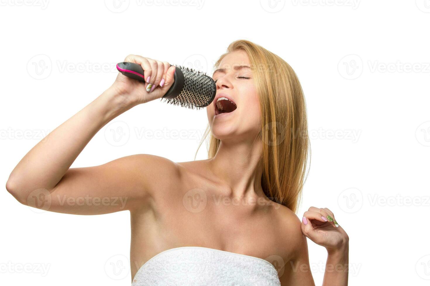 contento bella donna nel asciugamano cantando utilizzando pettine avendo divertimento foto