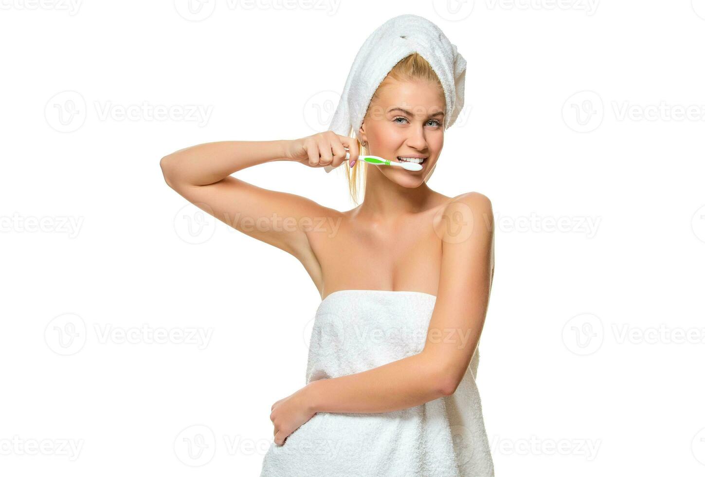 giovane attraente donna nel asciugamano spazzolatura sua denti con spazzolino foto