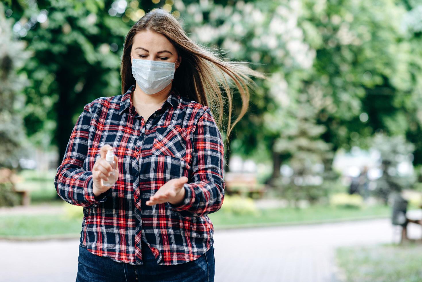 donna plus size in una maschera protettiva, si disinfetta le mani, all'aperto foto