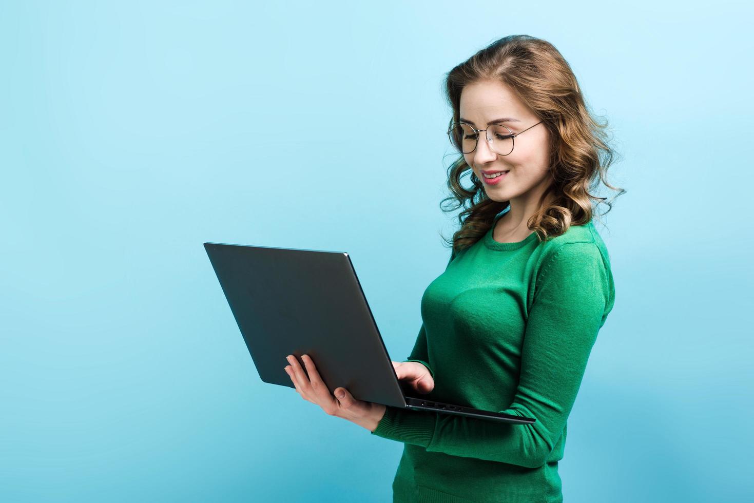 ragazza seria e sorridente con gli occhiali che lavora al computer portatile foto