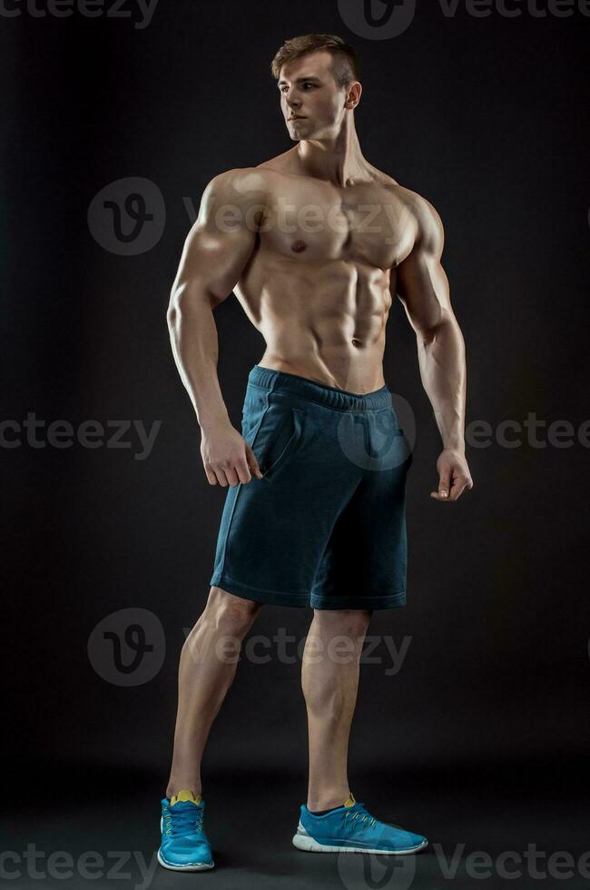 muscolare bodybuilder tipo fare in posa al di sopra di nero sfondo foto