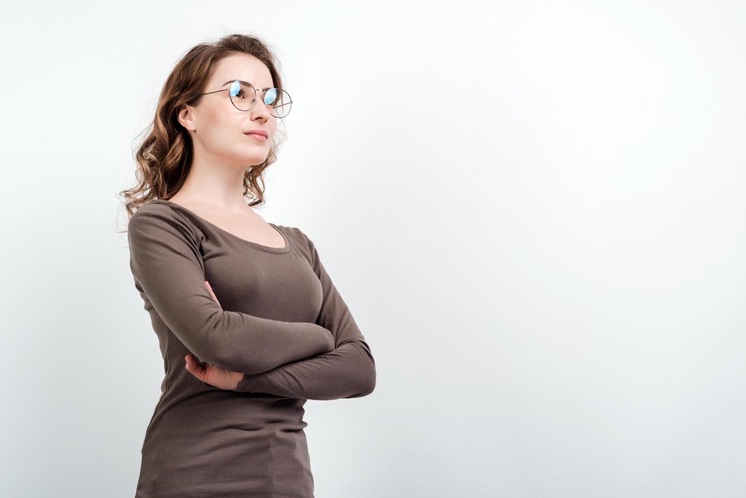 modello di donna in occhiali incrociò le braccia in posa isolata su sfondo bianco studio vuoto foto