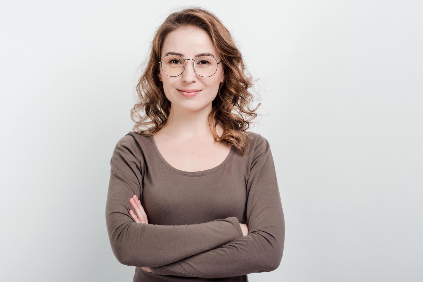 ritratto di donna con gli occhiali in piedi su uno sfondo di studio incrociò le mani foto