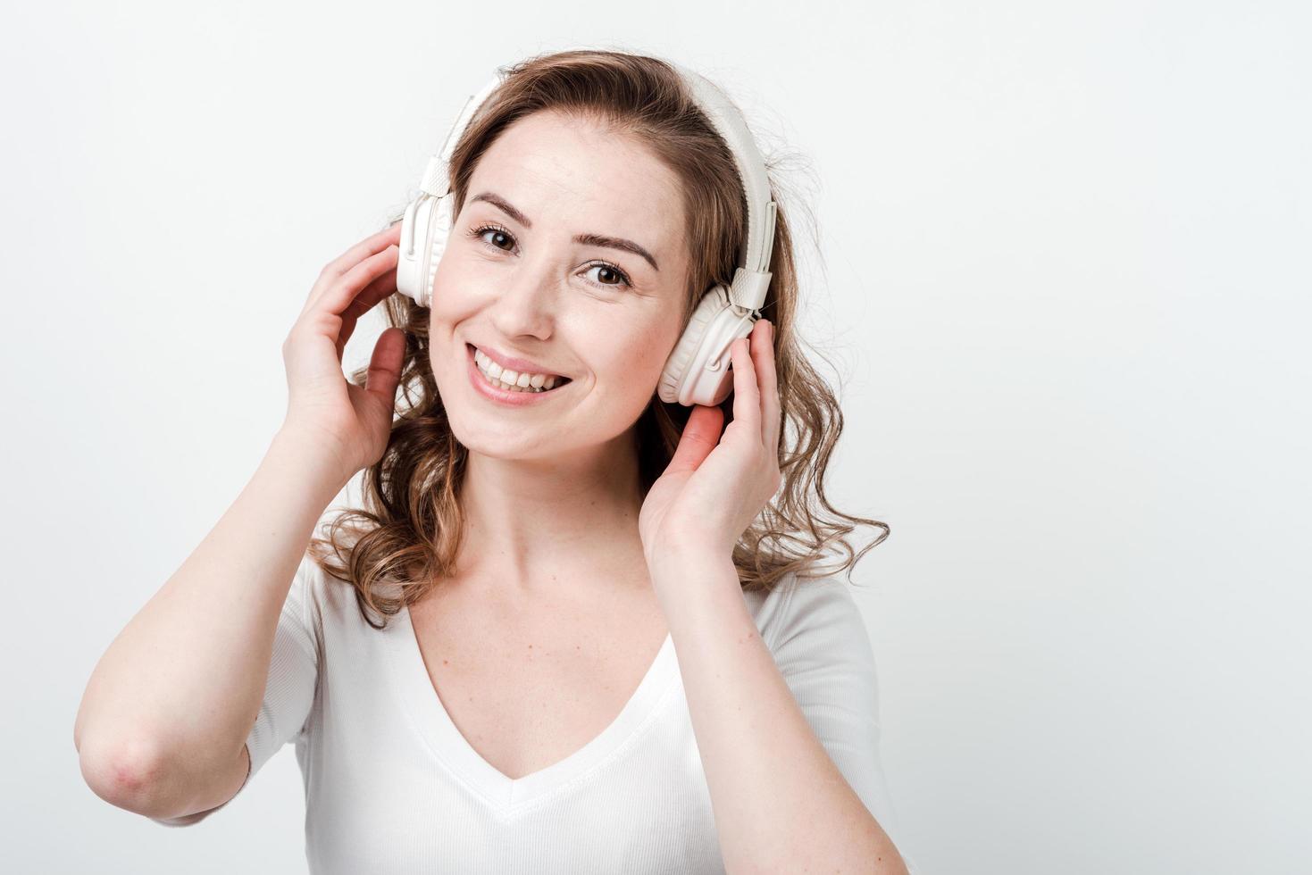 donna felice con gli auricolari wireless che guarda la telecamera foto