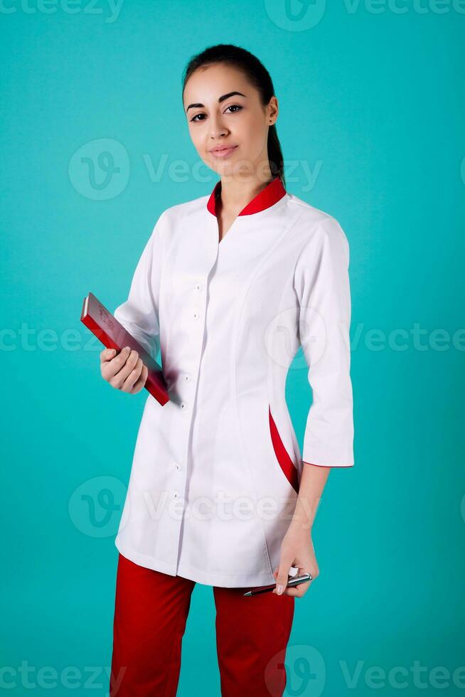 bellissimo donna medico Tenere rosso i pantaloni su turchese sfondo foto