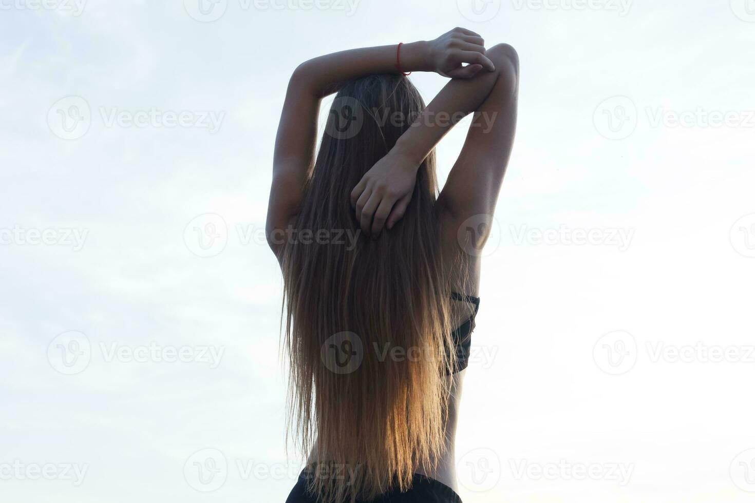 posteriore Visualizza di in forma giovane donna allungamento sua braccia all'aperto. foto