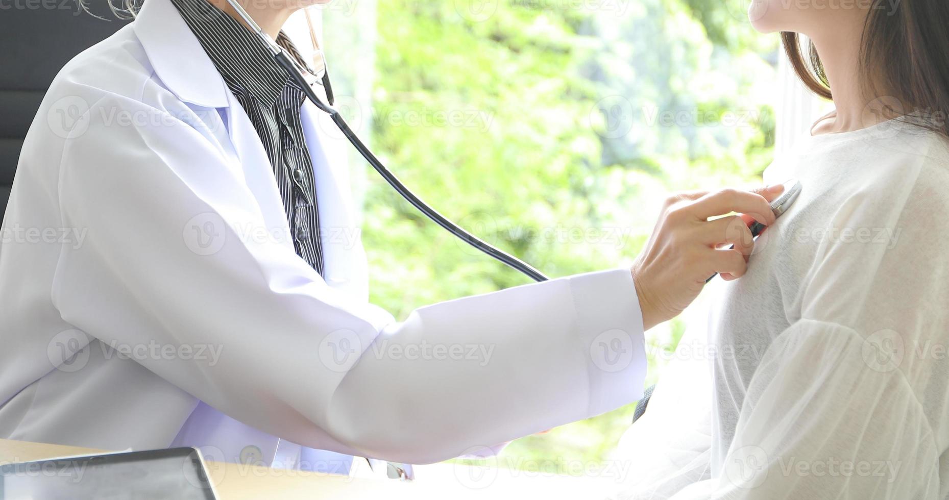 medico che utilizza lo stetoscopio per esaminare il paziente nel suo ufficio negli ospedali foto