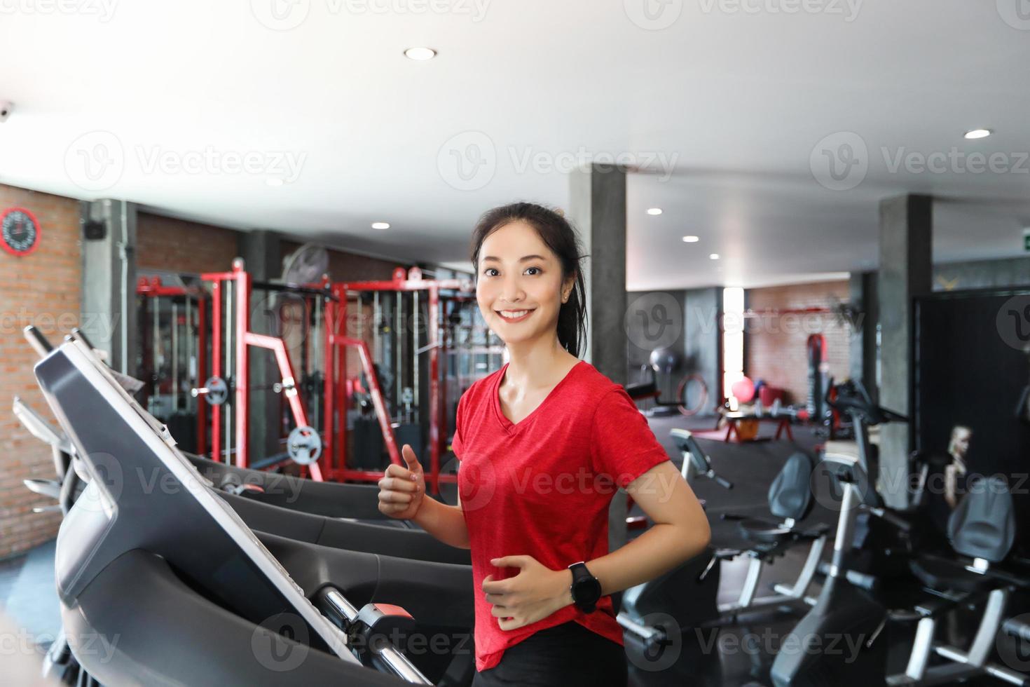 donne asiatiche che corrono scarpe sportive in palestra mentre una giovane donna caucasica sta facendo jogging sul tapis roulant foto