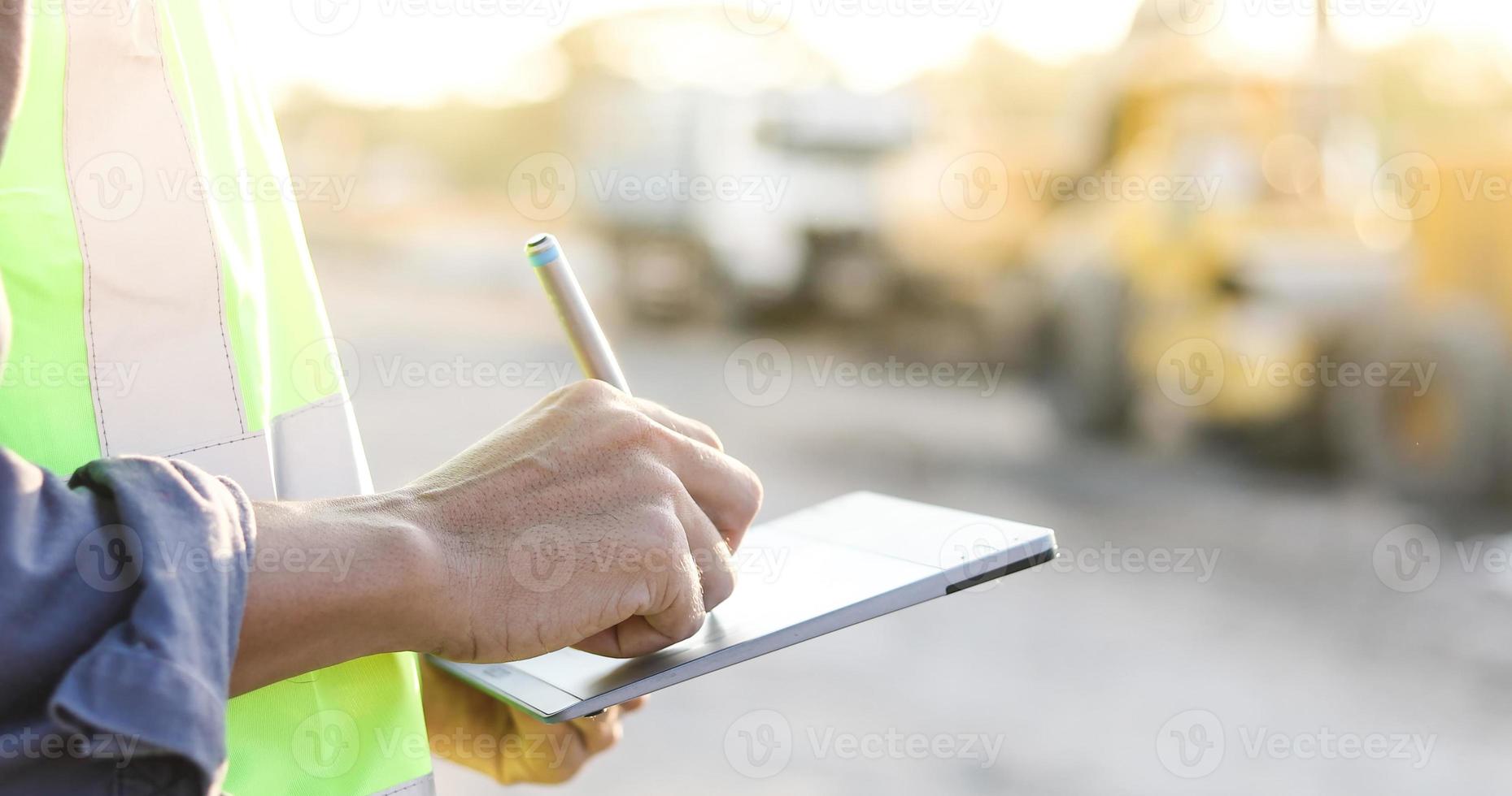 ingegnere asiatico con elmetto protettivo che utilizza computer tablet pc ispezione e lavoro in cantiere foto