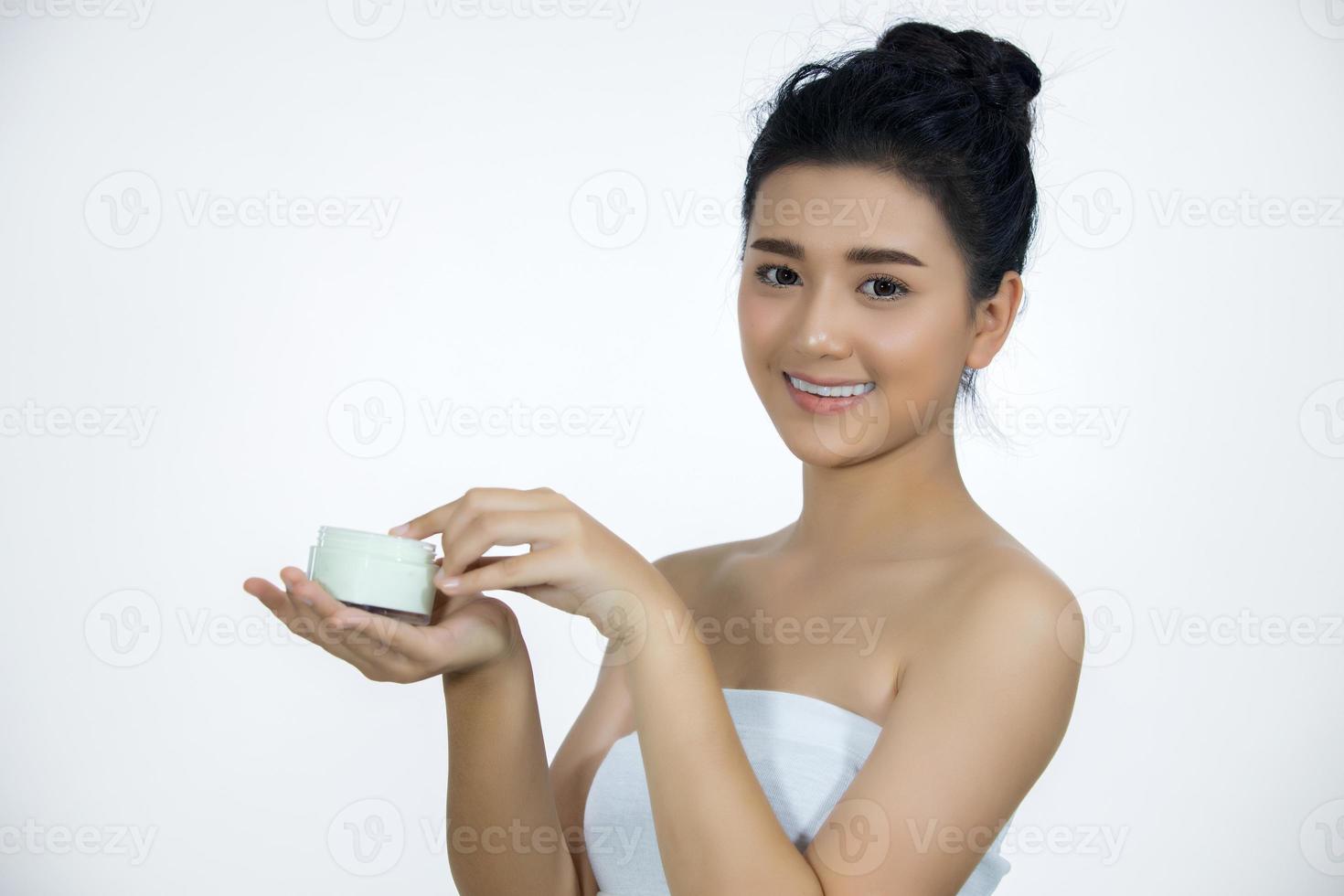 una bella donna asiatica che usa un prodotto per la cura della pelle, una crema idratante o una lozione che si prende cura della sua carnagione secca. crema idratante in mani femminili. foto