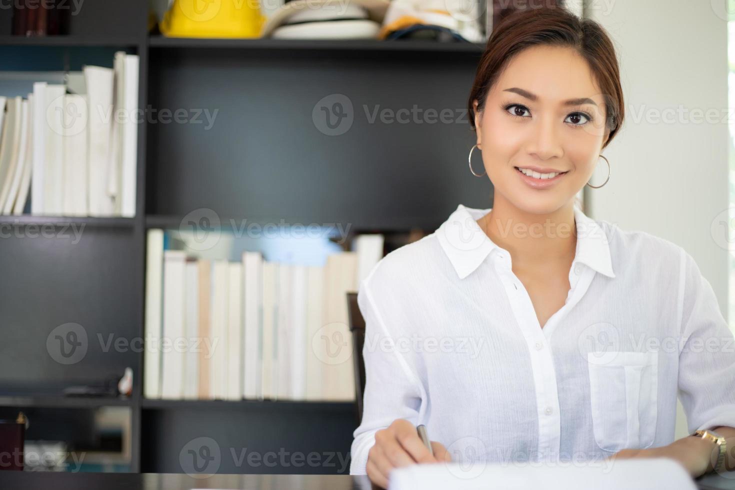 donne d'affari asiatiche che usano il taccuino e sorridono felici di lavorare foto