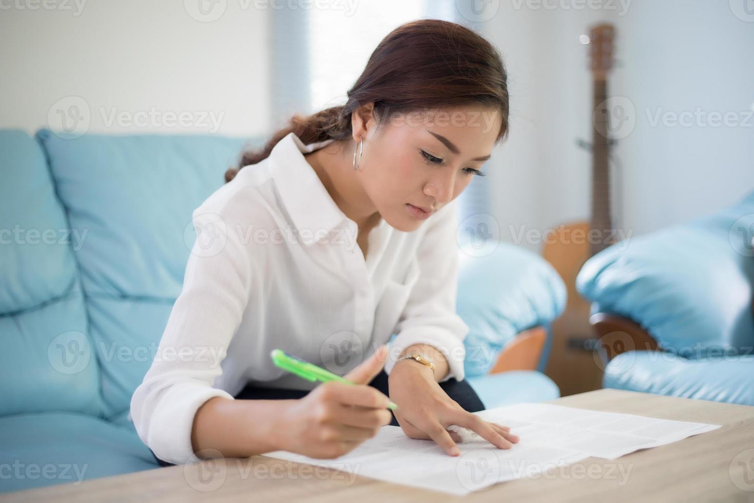 belle donne d'affari asiatiche che scrivono i dati che controllano il documento e sorridono felici per il lavoro foto