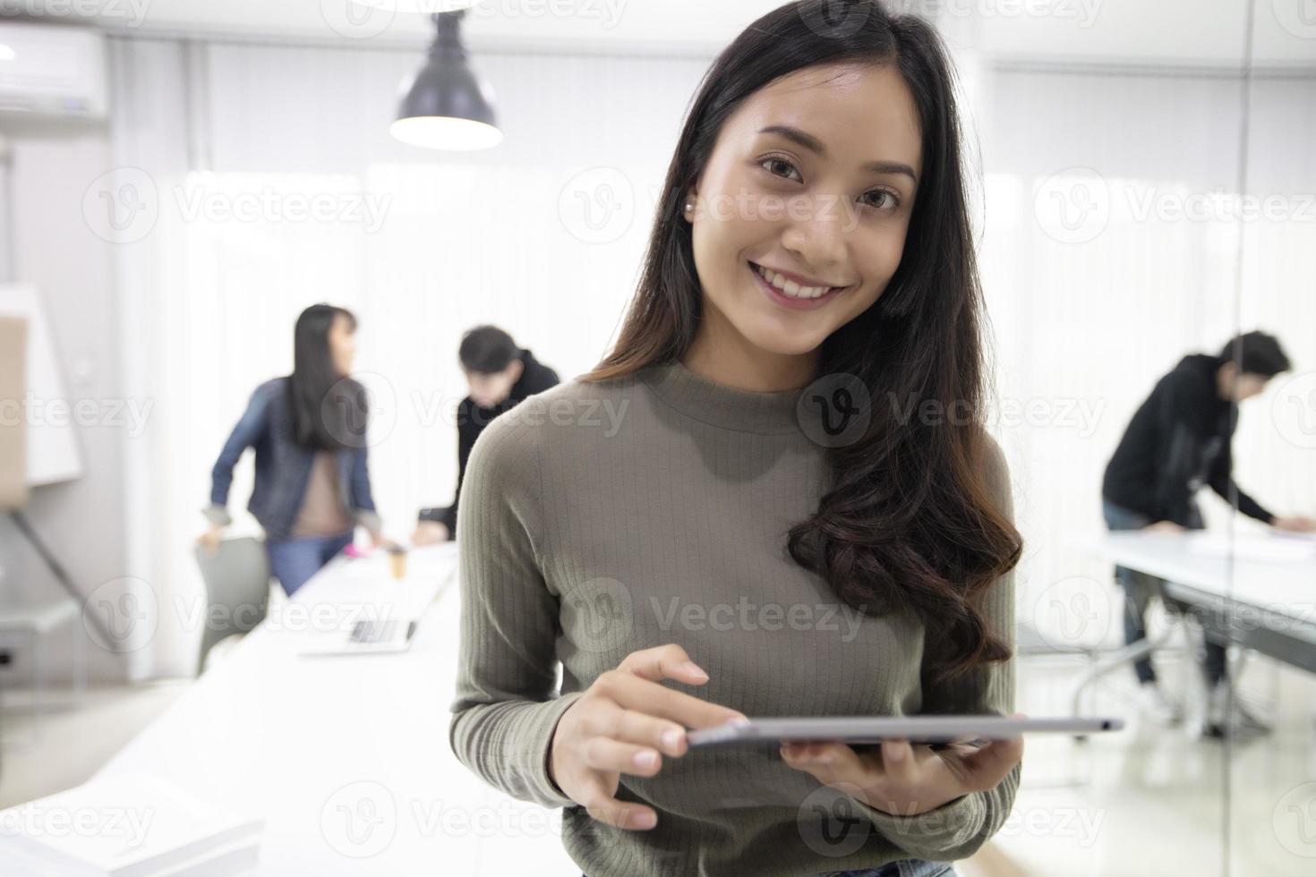 le studentesse asiatiche sorridono e si divertono e l'uso del tablet aiuta anche a condividere idee nel lavoro e nel progetto. foto