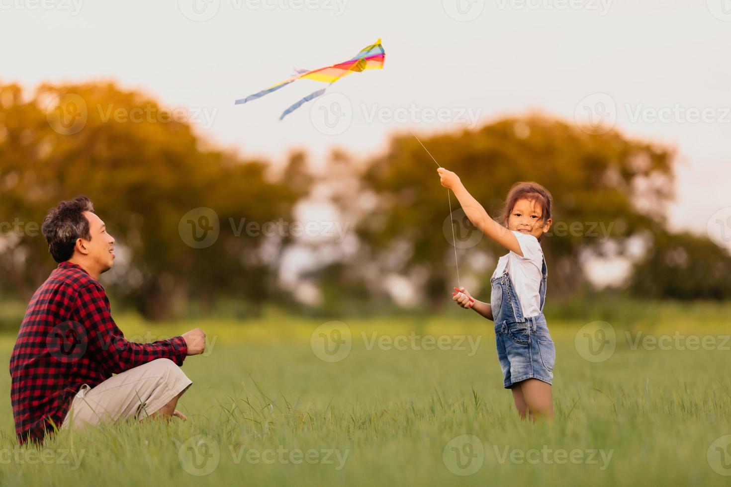 bambina asiatica e padre con un aquilone che corre e felice sul prato in estate nella natura foto