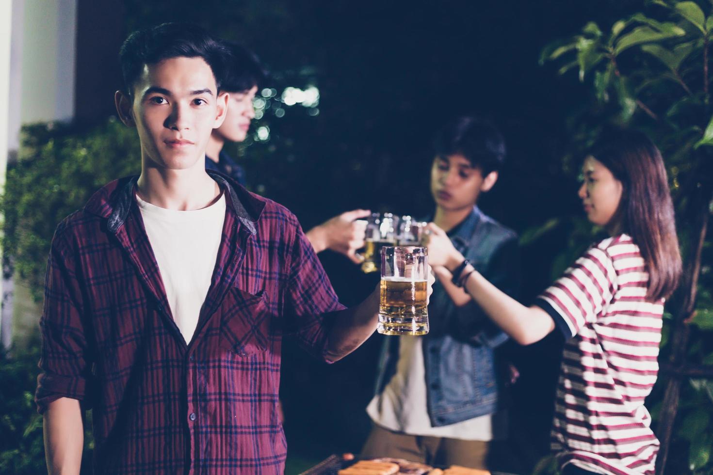 gruppo asiatico di amici che hanno barbecue in giardino all'aperto che ridono con bevande alcoliche di birra la notte? foto