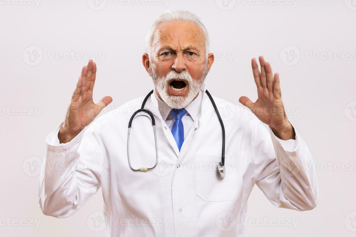 Immagine di arrabbiato anziano medico urlando su grigio sfondo. foto