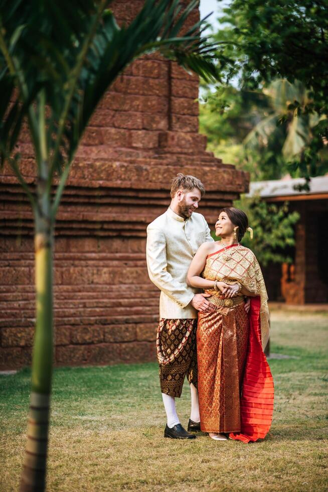 la sposa asiatica e lo sposo caucasico hanno un momento romantico con il vestito thailandese foto