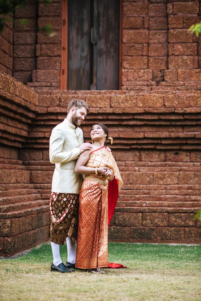 la sposa asiatica e lo sposo caucasico hanno un momento romantico con il vestito thailandese foto