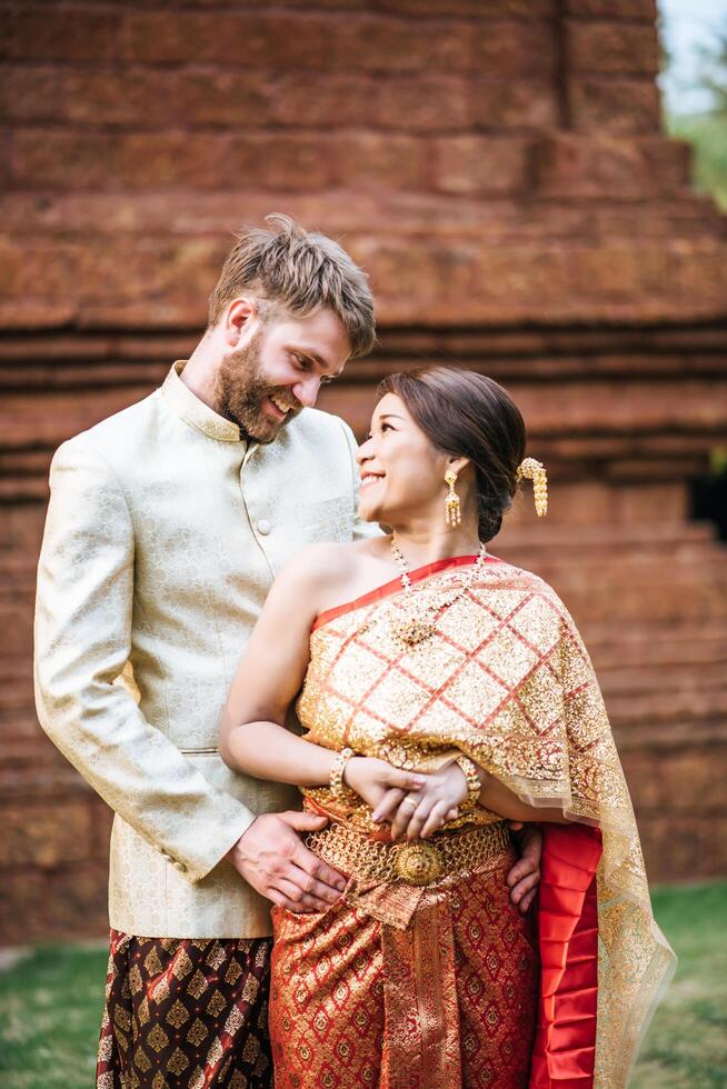 la sposa asiatica e lo sposo caucasico hanno un momento romantico con il vestito thailandese foto