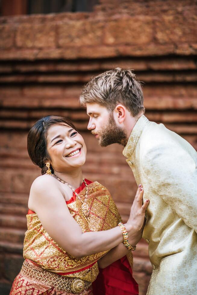 la sposa asiatica e lo sposo caucasico hanno un momento romantico con il vestito thailandese foto