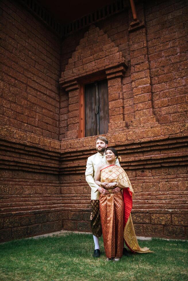 la sposa asiatica e lo sposo caucasico hanno un momento romantico con il vestito thailandese foto