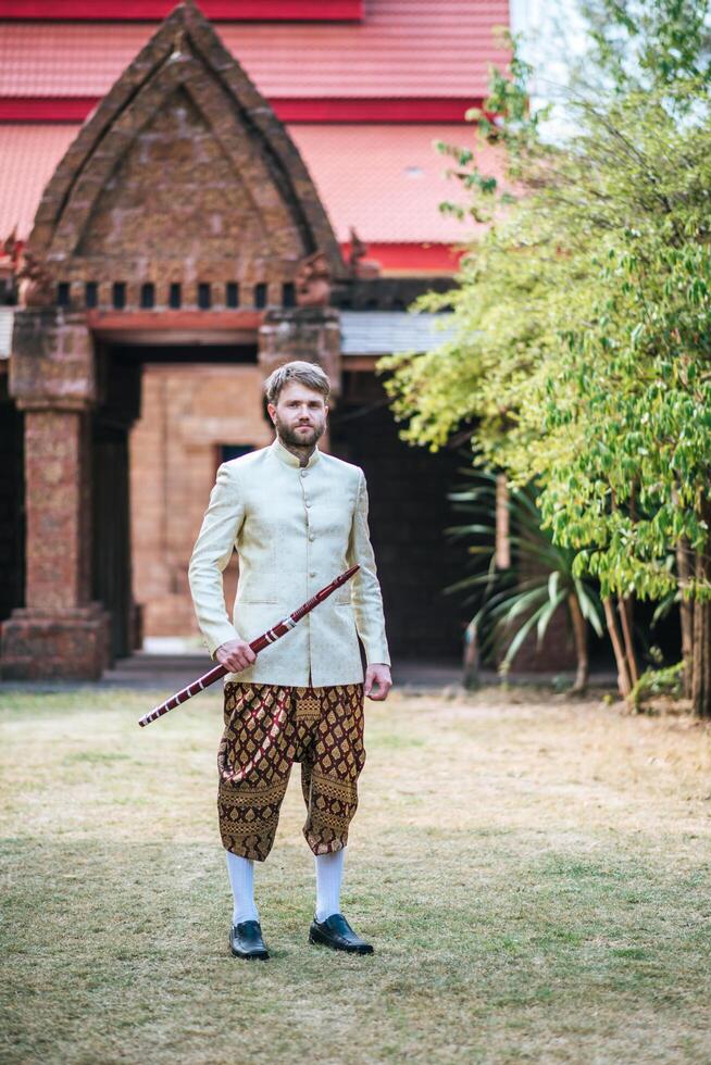 la sposa asiatica e lo sposo caucasico hanno un momento romantico con il vestito thailandese foto