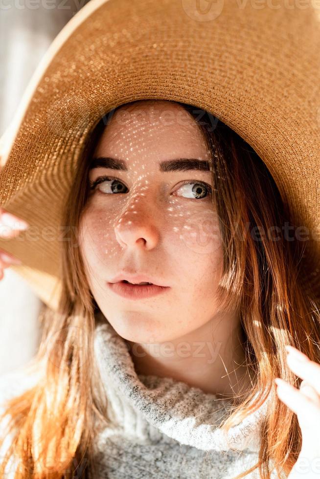 ritratto di una bellissima giovane donna con un cappello di paglia con un motivo di ombre sul viso e sul corpo foto